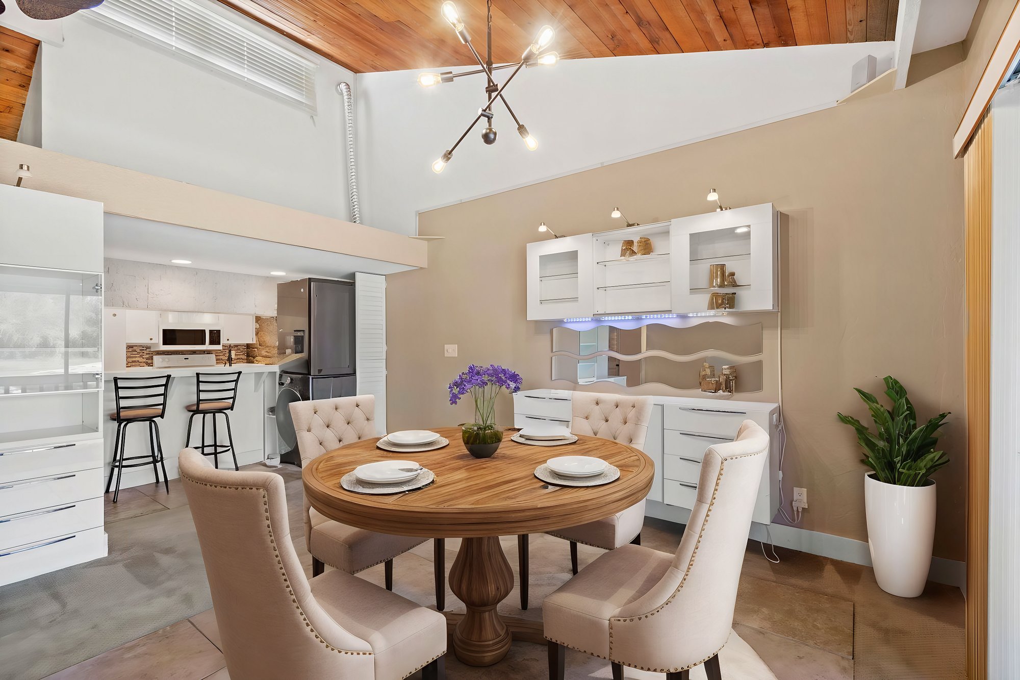 dining space with white cabinets and mirror on tall walls